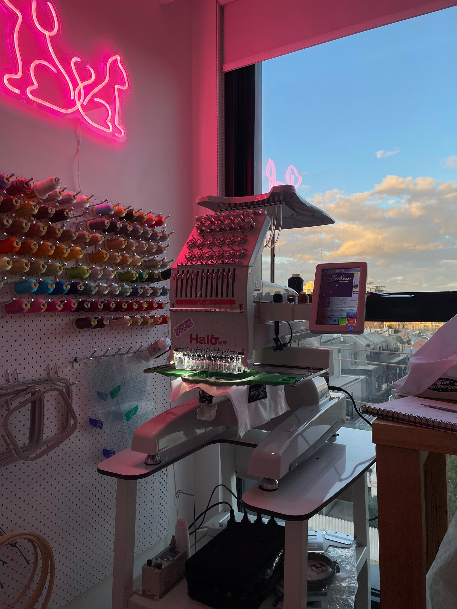 image of the skipping stitches studio and embroidery machine under a soft pink neon light