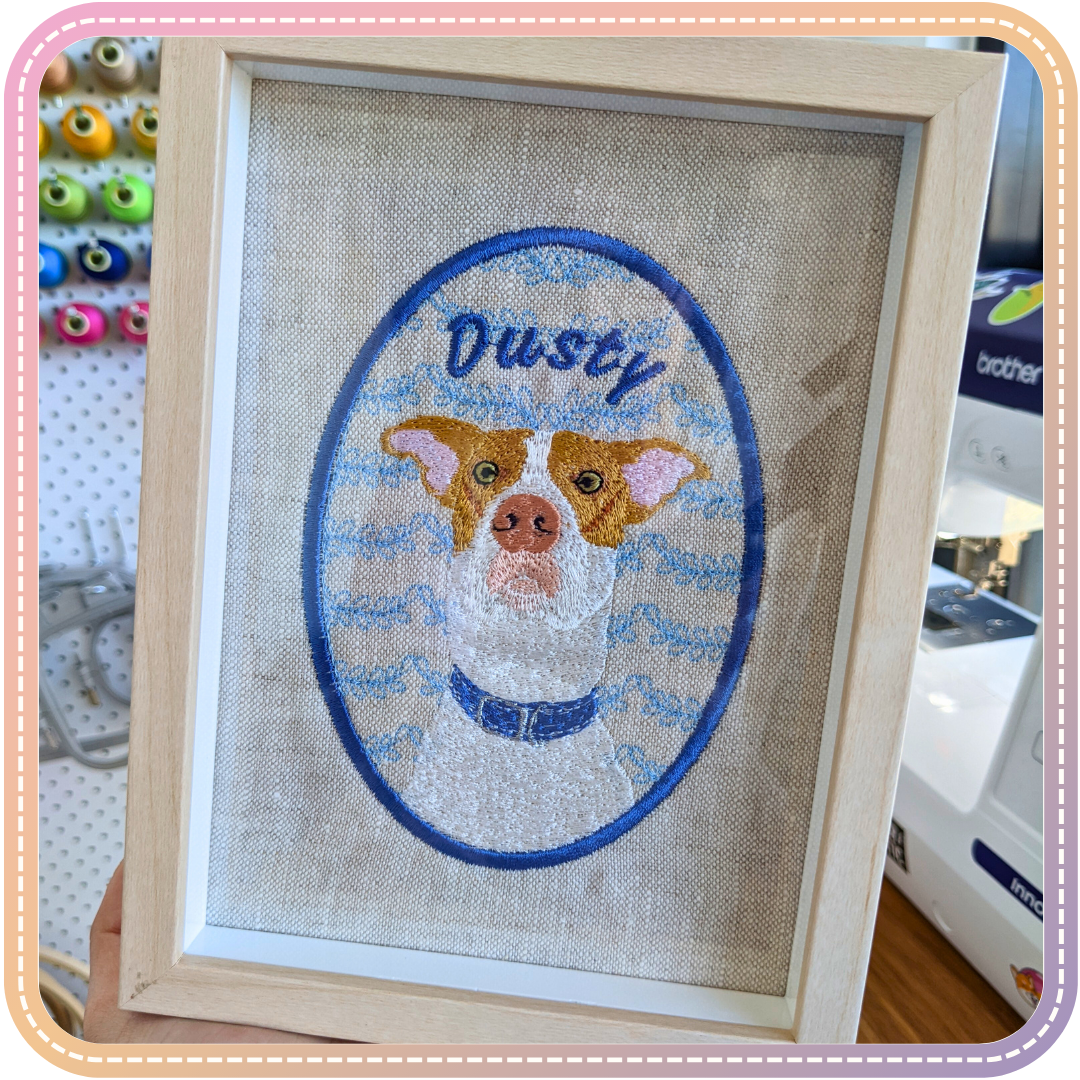 embroidery of a dog called Dusty in a small pale wood coloured frame